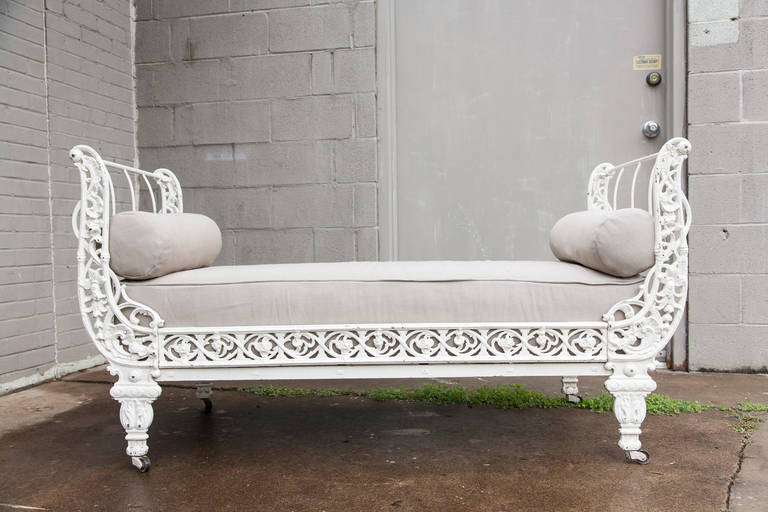 This circa 1860 Napoleon III white painted cast iron daybed features curved sides with an intricate floral scroll work. Originally used as a child's bed, its unusual smaller scale  makes it ideal for use as a banquette at the foot of a bed.  It