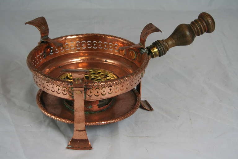 This rare eighteenth century copper and brass braisier hails from the city of Villedieu-les-Poeles, the French capital of copper artisans in Normandy, France.  It boasts ornately worked cut-out sides, hand riveted legs, and a hand-turned wooden