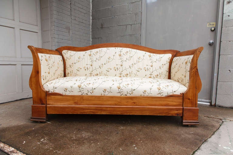 This handsome solid walnut Louis Philippe period settee features French Restauration style curved sides and classic Louis Philippe feet on casters.  Created in the early 1800's, this piece is designed for multiple uses.  As a sofa, the back hooks to