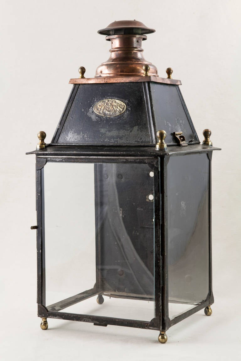 This late 19th century iron and copper railroad lantern has glass on three sides and stands on four brass feet. It bears its original Larroche Lampiste brass label from the company that produced it. The label reads 