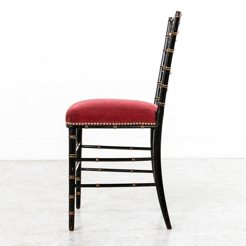 This elegant pair of black lacquer Napoleon III faux bamboo chairs are the perfect scale to slip into any space. With gold detailing and rose colored velvet seats this Classic pair will blend with all decors, circa 1860.