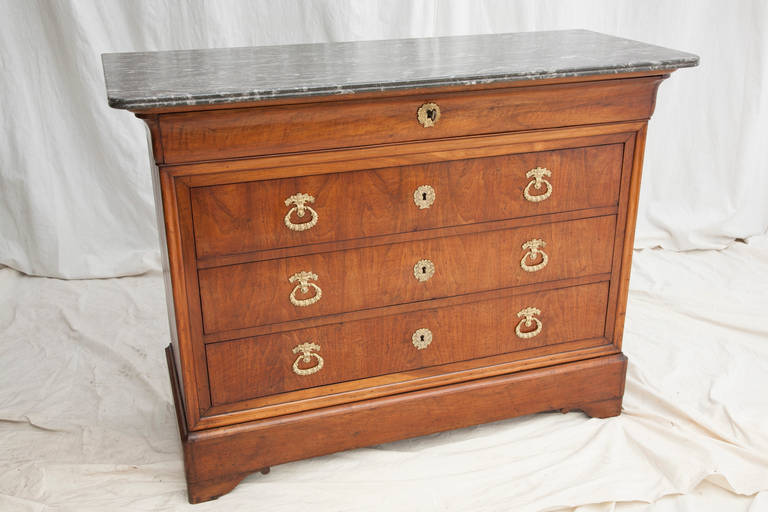 This bookmatched walnut Louis Philippe period commode has four drawers and a double beveled Saint Anne marble top. Its drawers are appointed with bronze pulls and key entries and have their original functioning locks and key, circa 1830-1848.