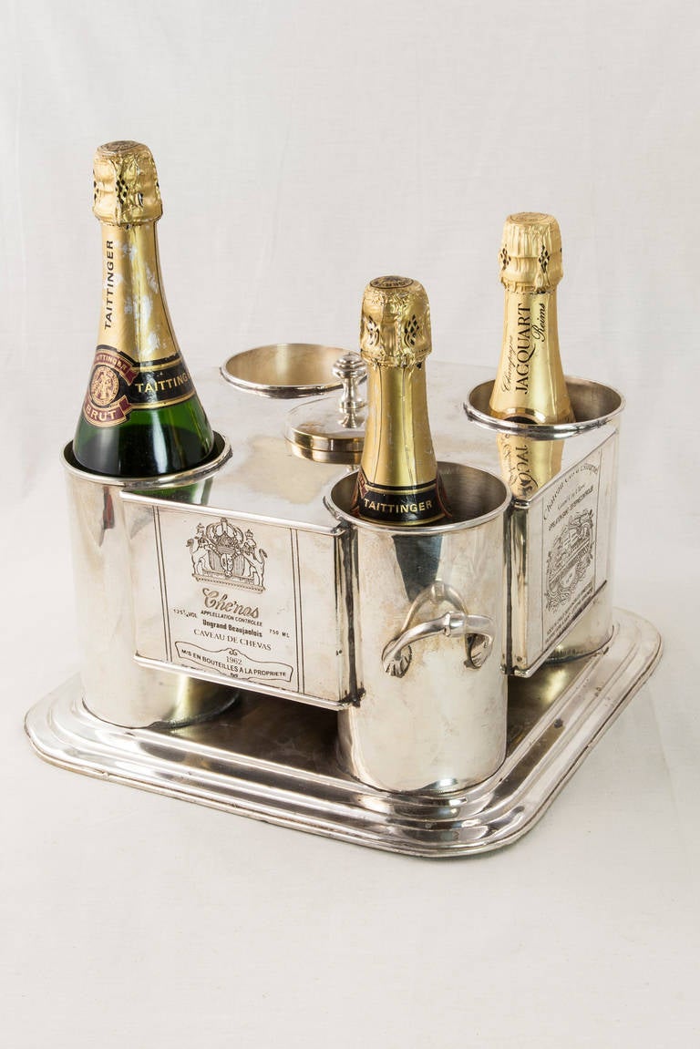 This mid-20th century silver plate wine chiller holds four bottles and has a central compartment with lid for ice. Each side has an engraved wine label from a French vineyard with the engraved years 1962 and 1966.