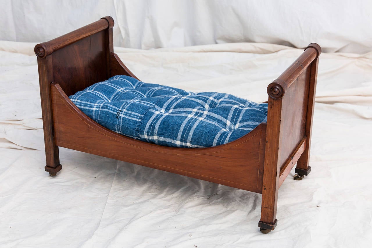 This delightful French Restauration period doll bed would make an elegant addition to a young one's playroom or an ideal bed for a small dog. Mahogany with lemonwood inlay, on original bronze casters, circa 1820.