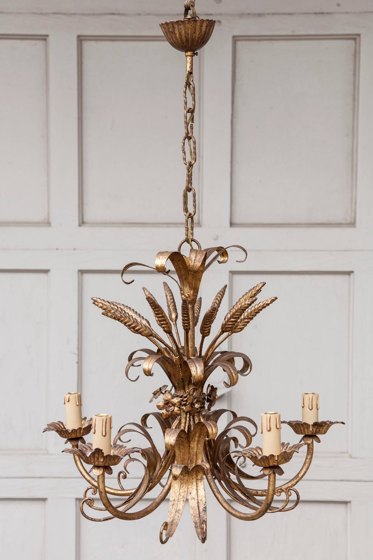 This Classic Regency motif chandelier featuring sheaves of wheat is a handsome blend of modern and historical styles. With a beautifully aged gilt tole surface and five candelabrum, it will cast a warm light for any space, circa 1920.