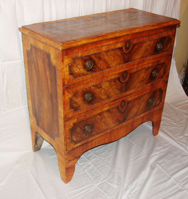 This delightful Italian pine three-drawer chest is cleverly painted with several faux exotic wood grains to create the illusion of panels that are highlighted with stringing on the top, sides and drawer fronts.  The drawers have brass escutcheons