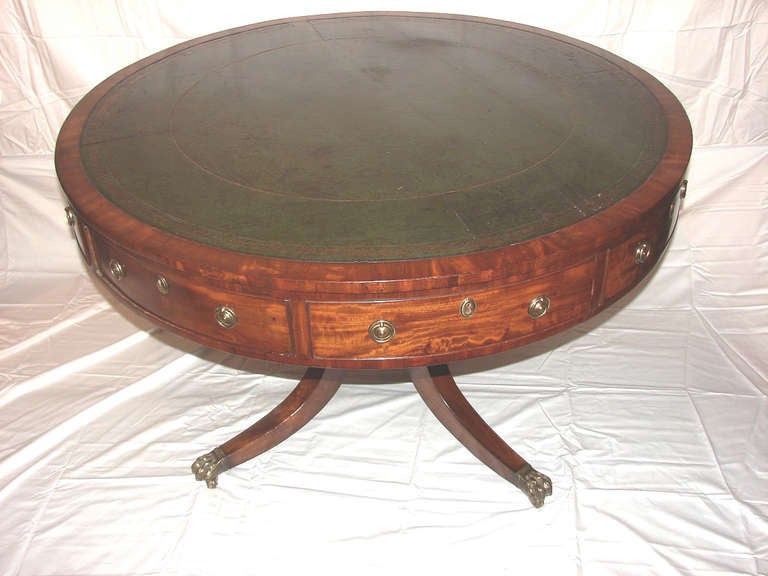 Georgian mahogany drum table with tapered sabre legs ending in brass paw feet with casters. The eight,cock beaded drawers have brass ring pulls and brass escutcheons. Four the drawers are operable and four are false drawers. The table top is inset