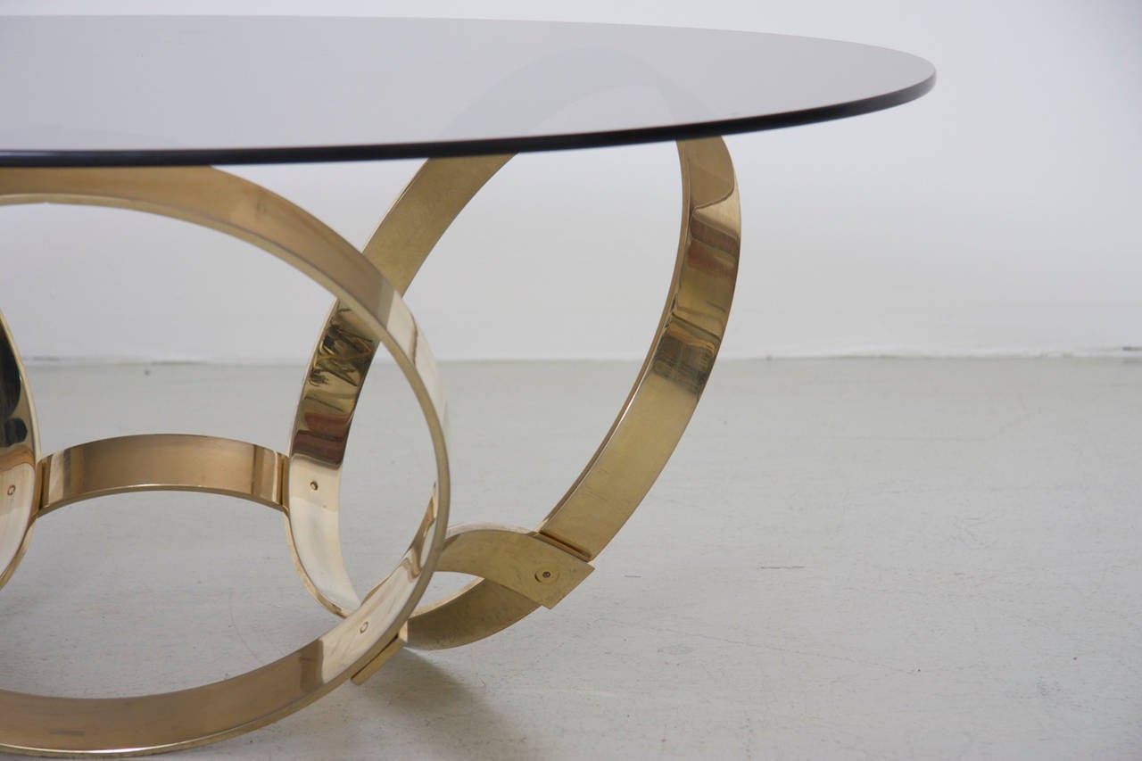 Wonderful coffee table with three massive geometric rings in brass with a floating glass top.Excellent condition.