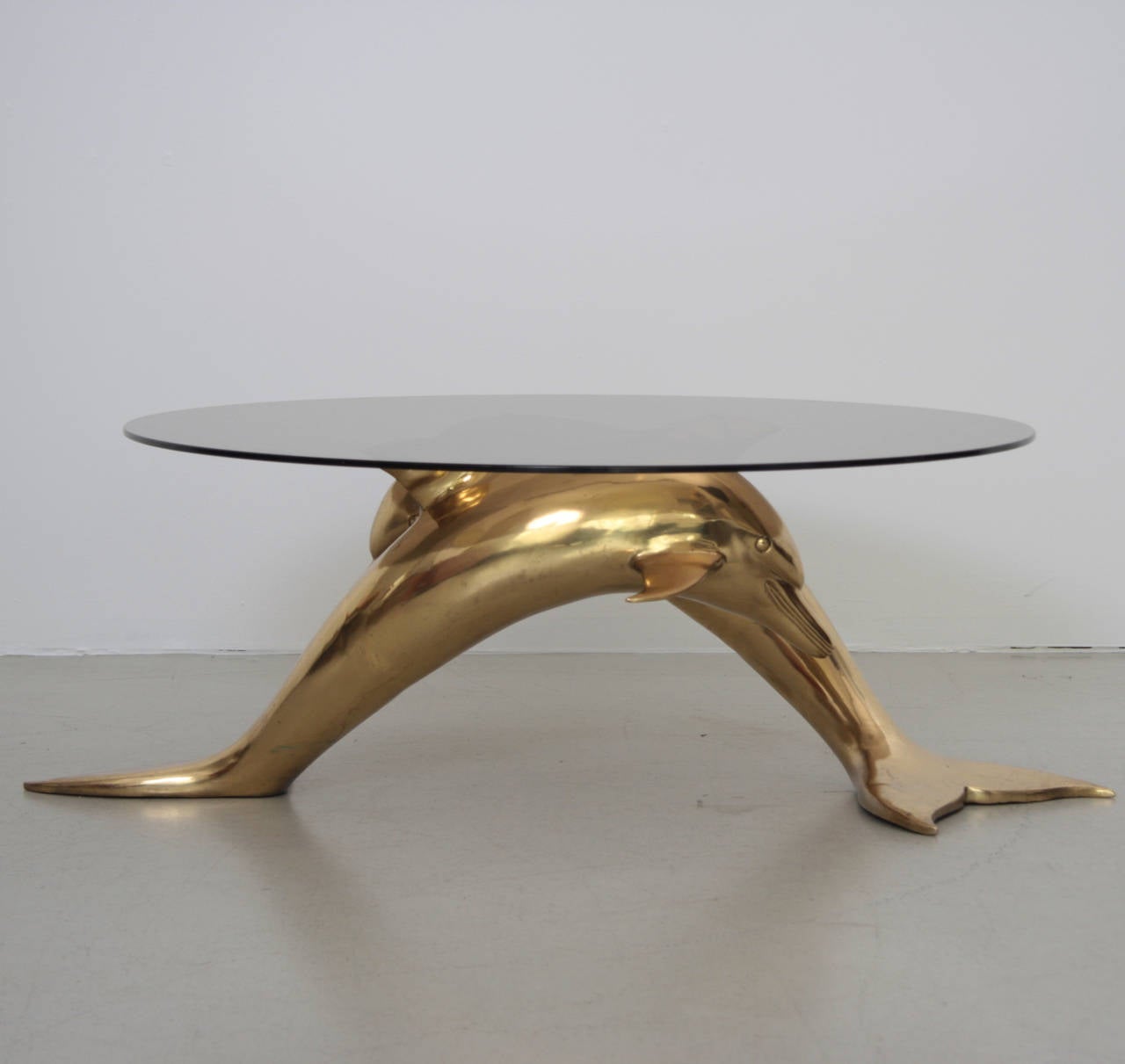 Very elegant and huge coffee table in brass and glass. The  glass table top is holded by two brass dolphins. The table is a really eyecatcher. The base shows scratches on the brass.

