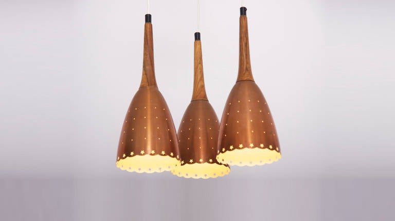 Impressive copper chandelier with performated shades and tropic wood details.
Scandinavian made. Hanging height of the shades can be changed in any wanted position.
Beautiful piece of Scandinavian lighting in nearly mint condition.
Shades are 37 cm