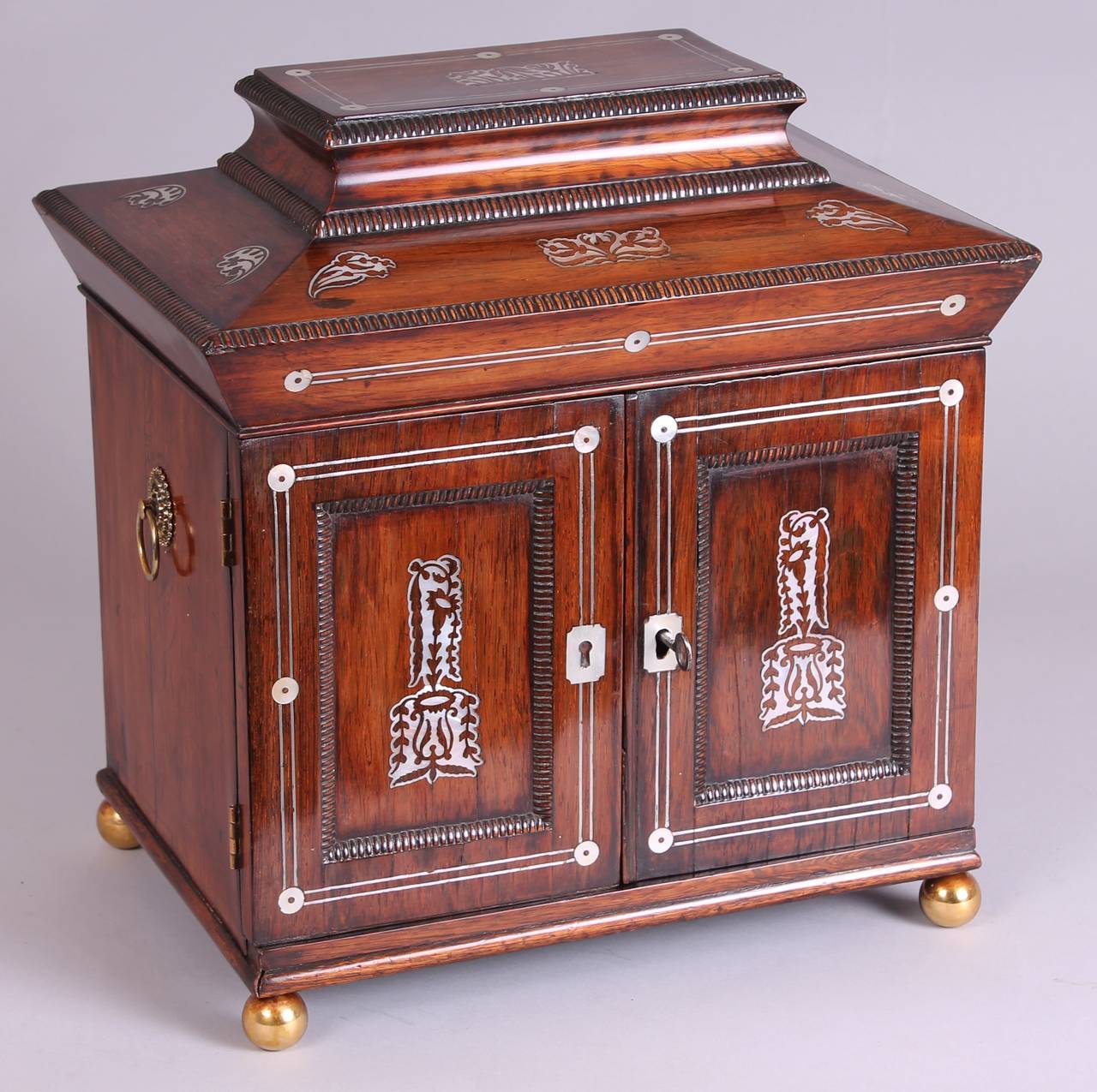 A William IV period rosewood and mother-of-pearl inlaid lady's table compendium; the deep hinged lid enclosing a fitted work-box with its original blue silk lining, and a pair of doors with three drawers behind; the lower one forming a removable