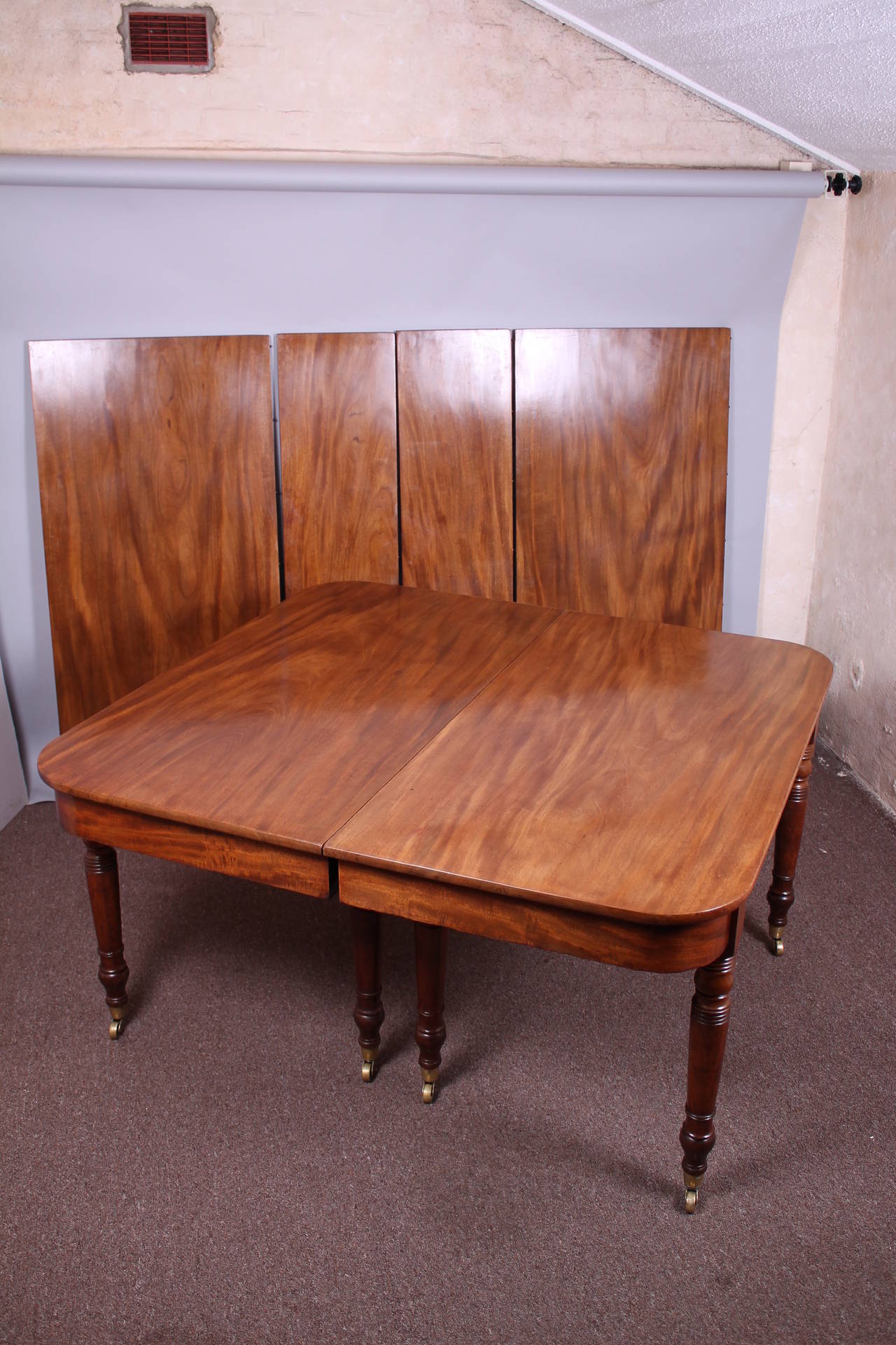 A good George IV period golden mahogany extending dining-table with two end-tables on four ring-turned legs and brass cup-castors; the substantial telescopic frame extends to take combinations of two large and two small leaves. Circa 1825 

53