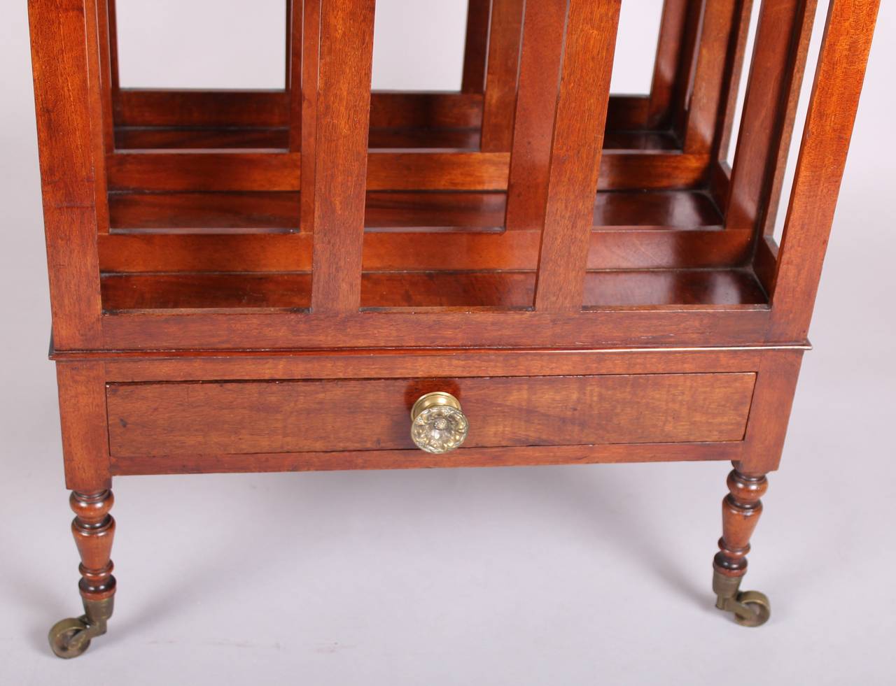 George III period mahogany Canterbury with three compartments and a single drawer, on turned legs with brass cup-castors.