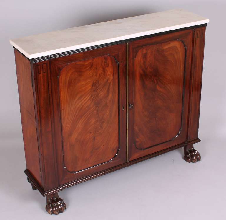 George IV period mahogany side-cabinet of fine quality and unusually shallow proportions fitted with two adjustable shelves, enclosed by a pair of doors with shaped panels and flanked by stiles with inlaid ebony line decoration, on boldly-carved paw