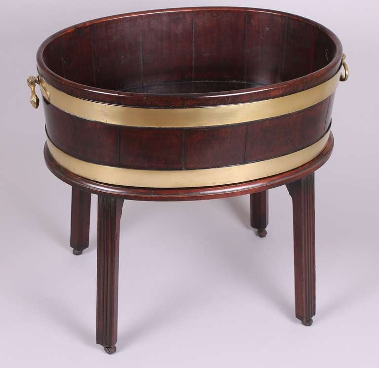 George III period mahogany brass-bound wine-cooler of coopered construction and on its original stand with moulded legs,

circa 1780.
