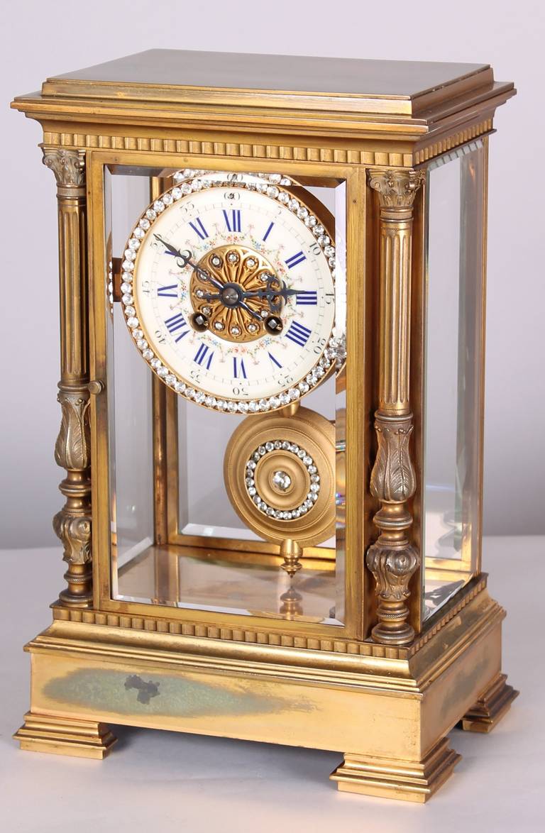 Late 19th century French gilt brass mantel clock; this rather opulent clock has a 20 day gong striking movement, fitted with a garlanded enamel dial and a bezel and pendulum surrounded by paste brilliants; the heavy case with four bevelled glasses,