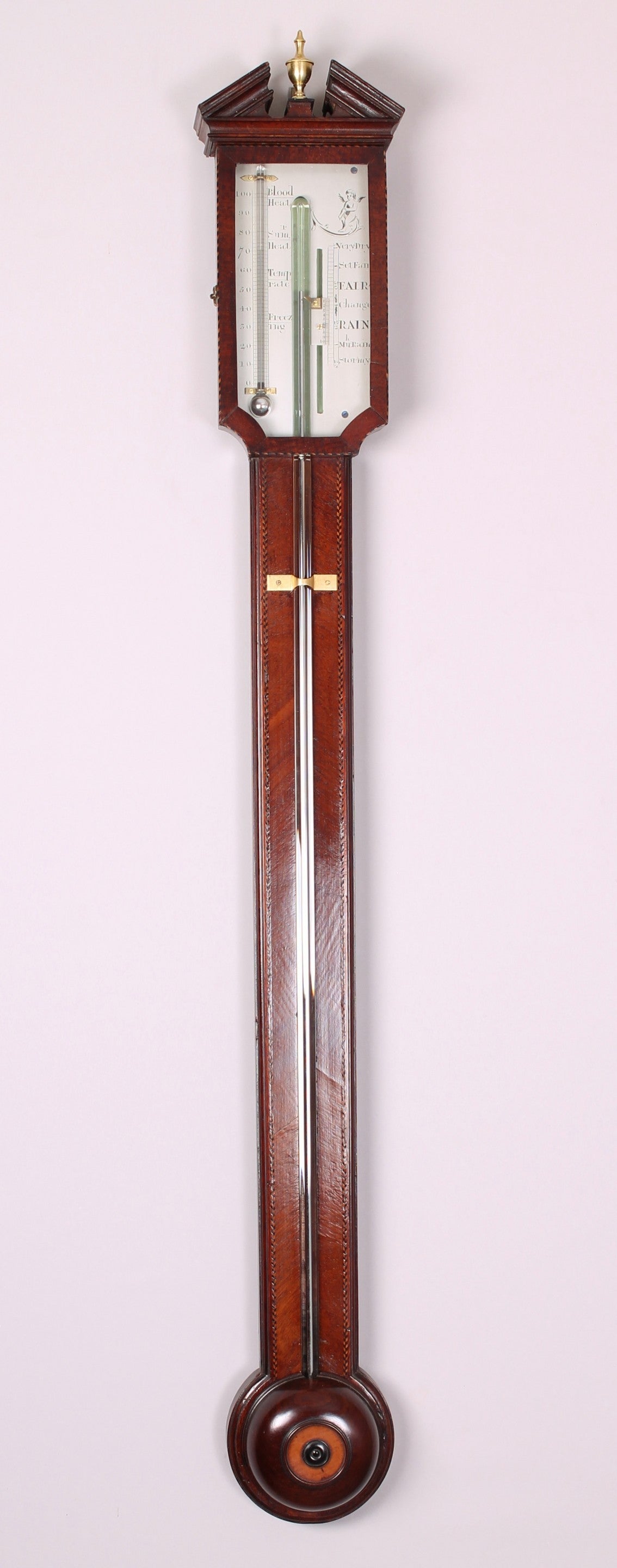 George III period mahogany stick barometer; the un-signed silvered register enclosed by a hinged and glazed door; the richly-coloured case with black-and-white boxwood cable and chequered stringing, a turned cistern-cover with an inlaid boxwood