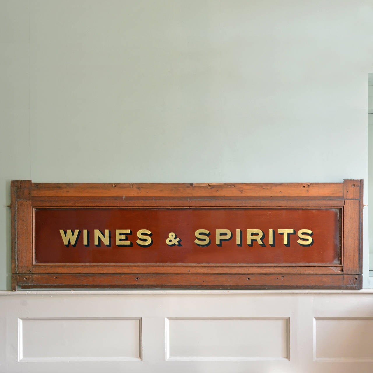 A reverse painted and verre eglomise signboard, on maroon ground with hardwood framing.

221cm wide, 68cm high.

Available to view at Brunswick House, London.