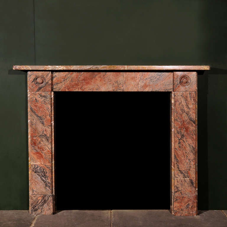 A Regency Ashburton marble bullseye chimneypiece, the shaped rectangular mantel above plain frieze flanked by deep carved bullseye details, above flat fronted jambs and simple foot blocks. 

Aperture height 91.5 cm x 86 cm wide.

Available to