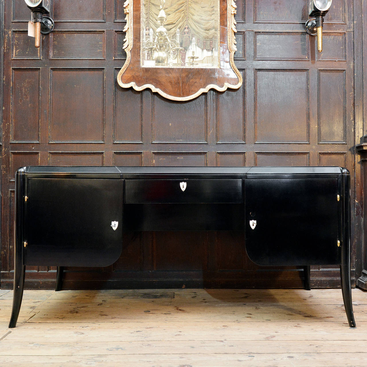 A 1930's Swiss black lacquered desk, the inverse breakfront top above a pair of cupboards flanking central drawer with open shelves opposing, on splayed sabot legs. 

Available to view at Brunswick House, London.

78cm high, 166cm wide, 88cm