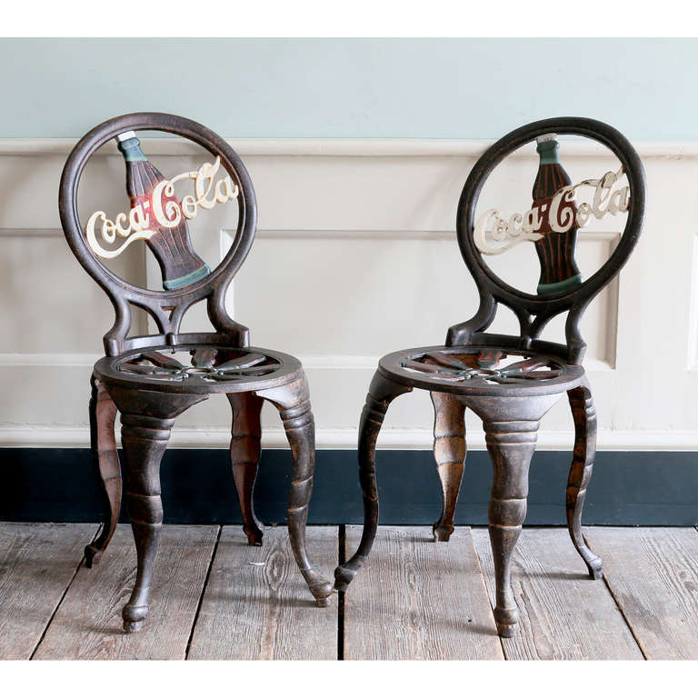 A rare pair of 'Coca-Cola' cast iron chairs, c.1950, the back inset with iconographic bottle and logo, on modified cabriole legs.

Available to view at Brunswick House, London.