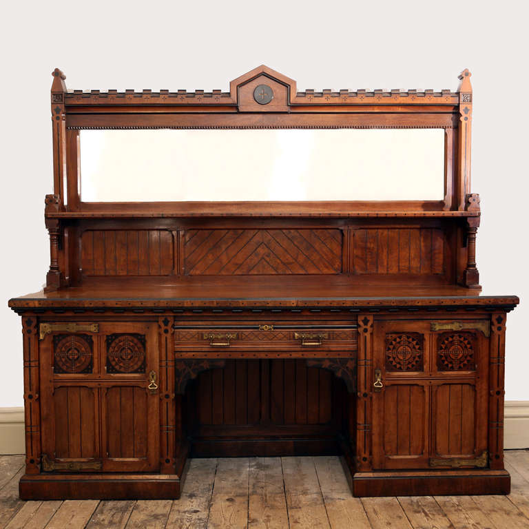 An imposing Reformed Gothic oak, walnut, ebonized and marquetry sideboard,
in the manner of Charles Bevan, circa 1870, the mirrored super-structure with castellated top and shelf supported by ring turned columns, the crossbanded top with ebonised