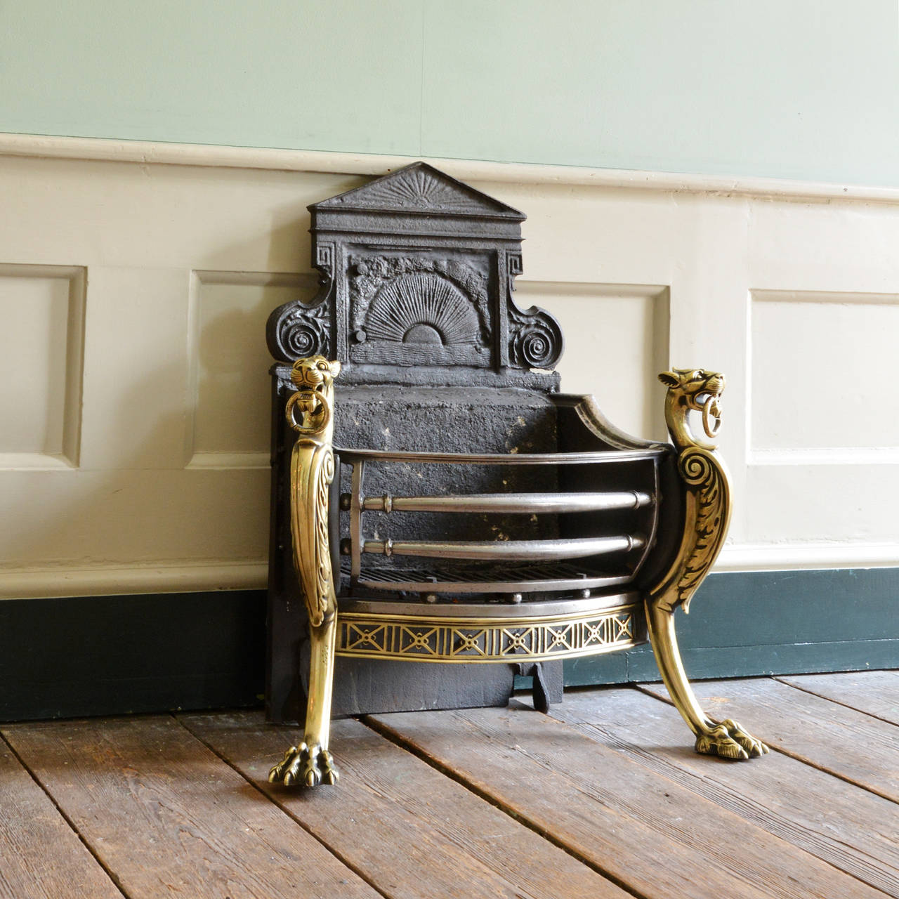 A Victorian iron, steel, and brass firegrate, the cast backplate above basket, flanked by outset monopodia with hairy paw feet.

Available to view at Brunswick House.

79cm high, 70cm wide, 35cm deep.