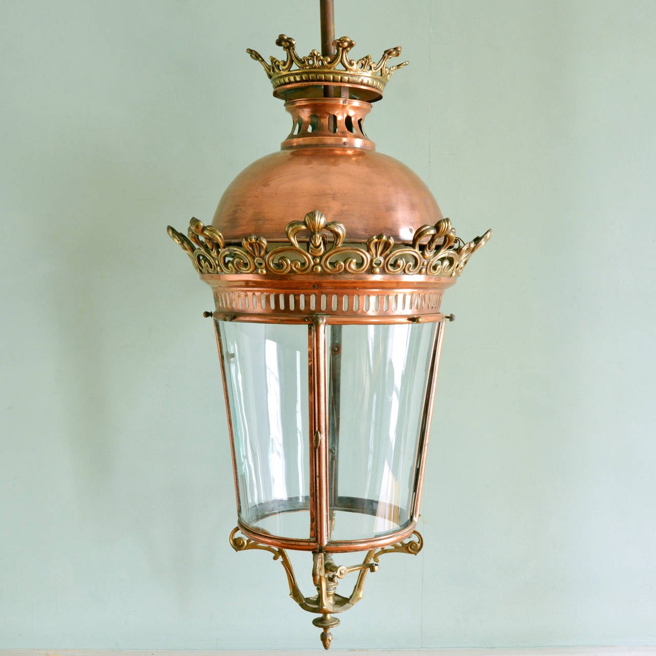 An impressive copper and brass entrance hall lantern, late nineteenth century, the decorative brass ceiling rose above coronet shaped finial leading to domed lid decorated with well cast brass details of s and c scroll design centred by stylised