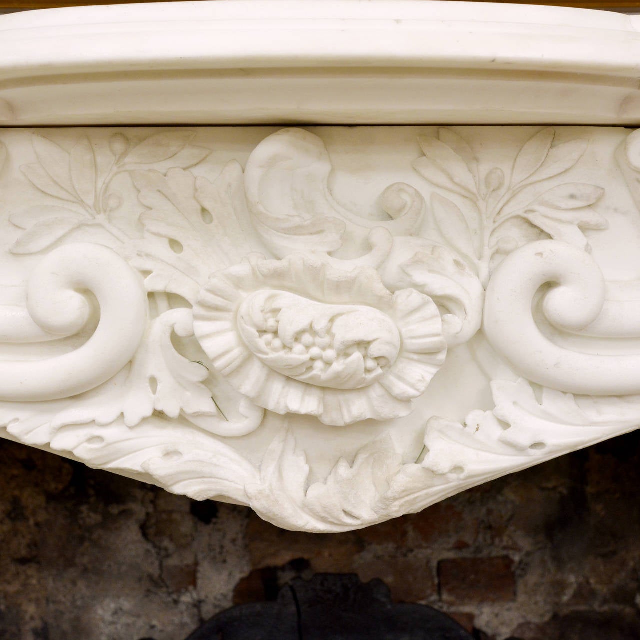 A large English Rococo Revival White Carrara marble chimneypiece, attributed to Benjamin Wyatt c.1830-1835, the serpentine shelf above frieze of leaves, flowers and scrolls carved in deep relief, flanked by acanthus detail above scallop shell motif,