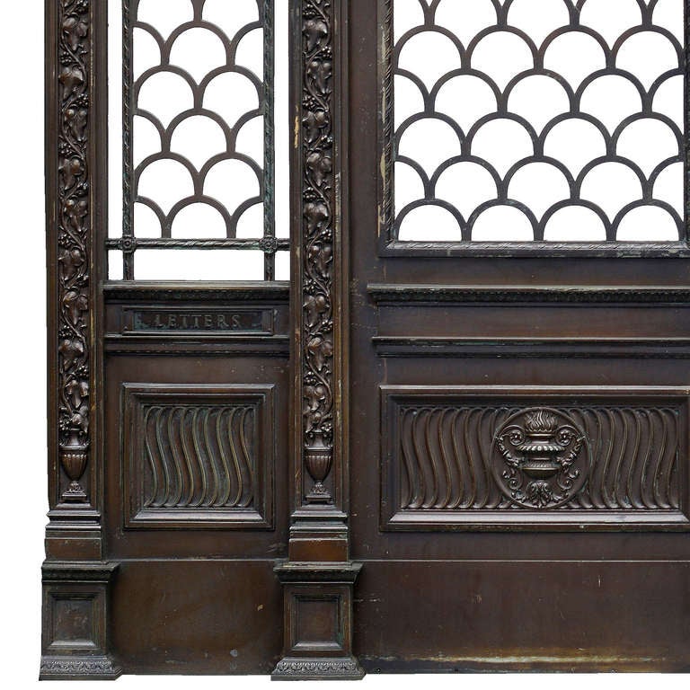 The Empire House Doorway, cast by H. H. Martyn & Co. Ltd., circa 1925.  Attributed to Walter Gilbert.

The cresting with a cabochon held by two putti bearers with scrolled acanthus tails, flanked to each side by twin flambeau urns interspersed by