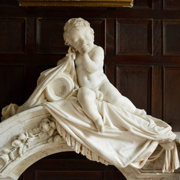 A highly distinct late nineteenth century marble chimneypiece, made of Italian Carrara and Statuary white marble.

The beautifully carved putti clutching folds of material, which cascade over a shaped frieze again deeply carved with trailing