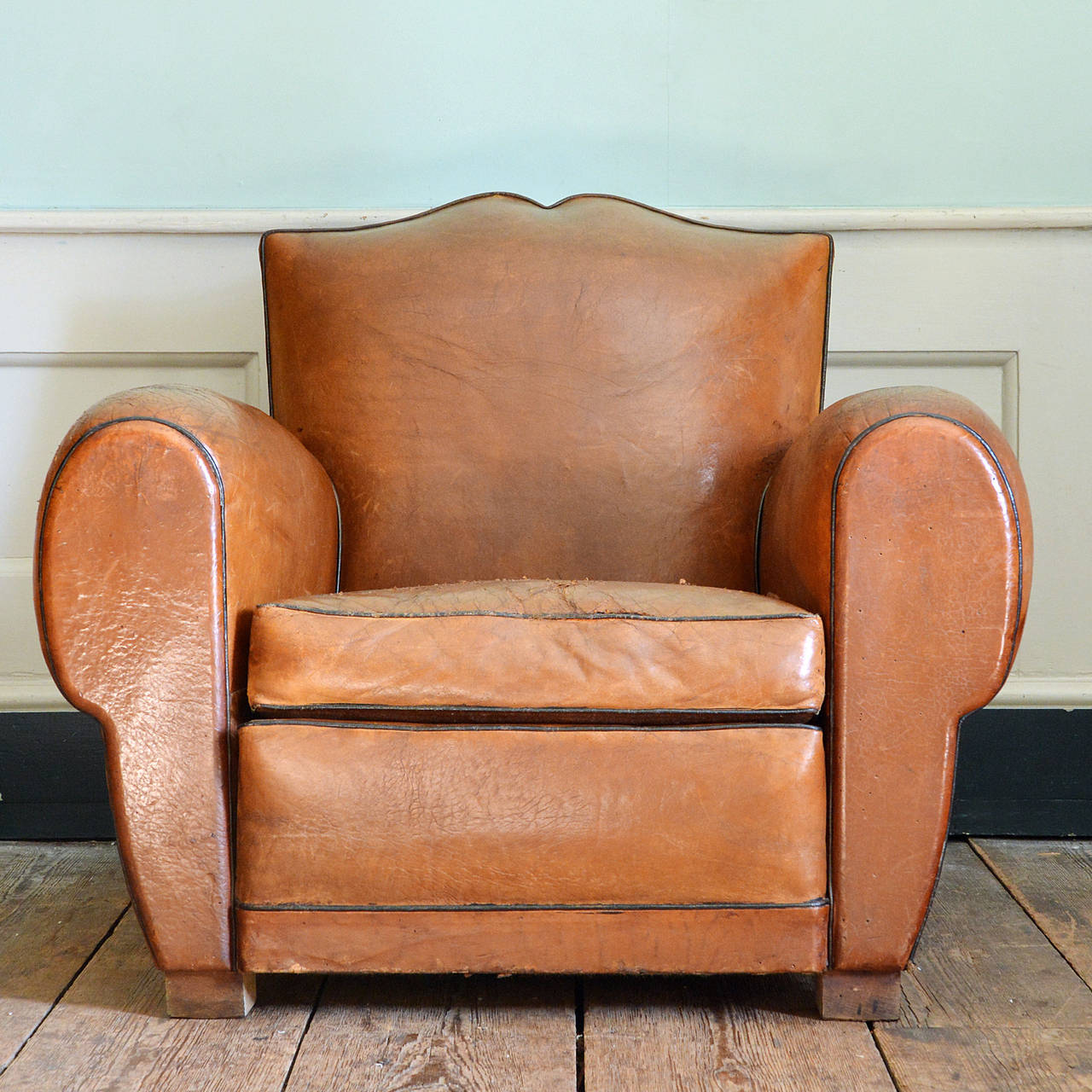 A pair of tan leather upholstered club chairs, French circa 1930, with 'moustache' back and black piping on beech feet.

Available to view at Brunswick House, London.

Width 92cm, height 79cm, depth 90cm. Seat height 39cm.