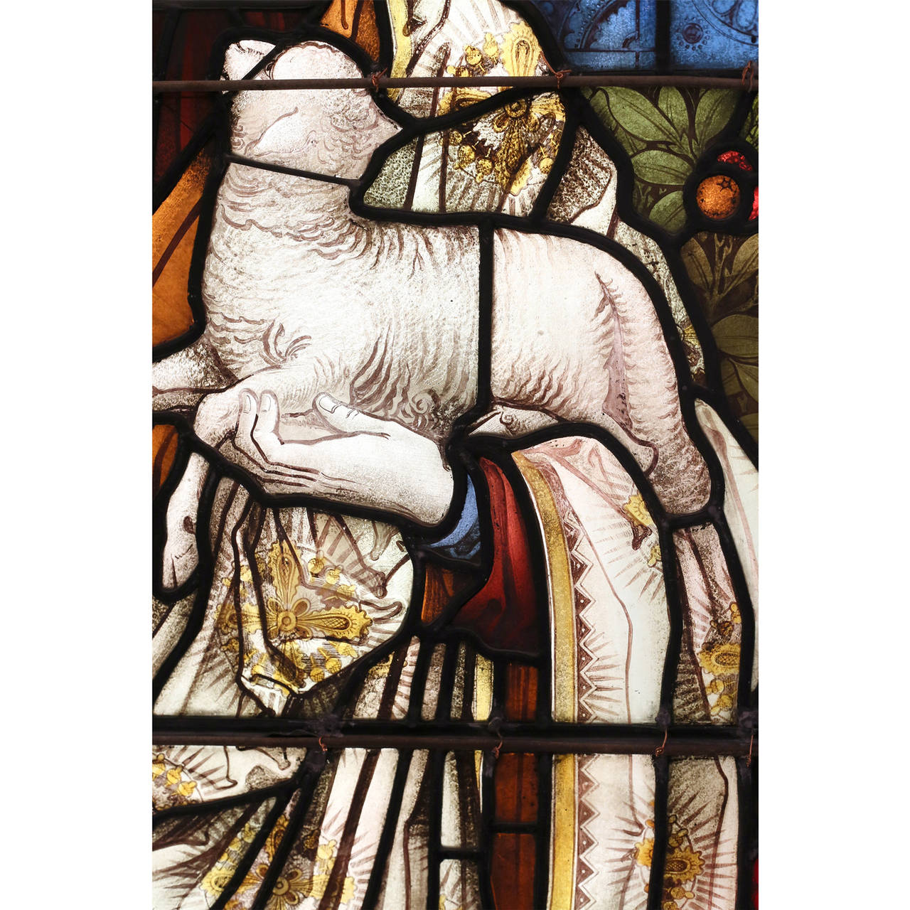 A stained and painted glass window depicting the Good Shepherd, circa 1890, by Carl Armquist of Shrigley & Hunt, the leaded glass panel depicting the robed Christ figure standing against a foliate back-drop and holding the Lamb.

Available to view