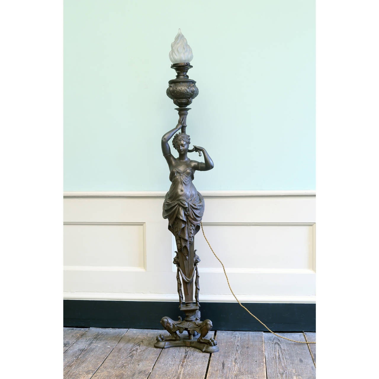 A French Spelter floor lamp, late 19th century, modelled as a robed female on zoomorphic triform base, topped with flambeaux shade. Converted to electricity from oil. 

Available to view at Brunswick House, London.

Height 163cm, width 34cm.