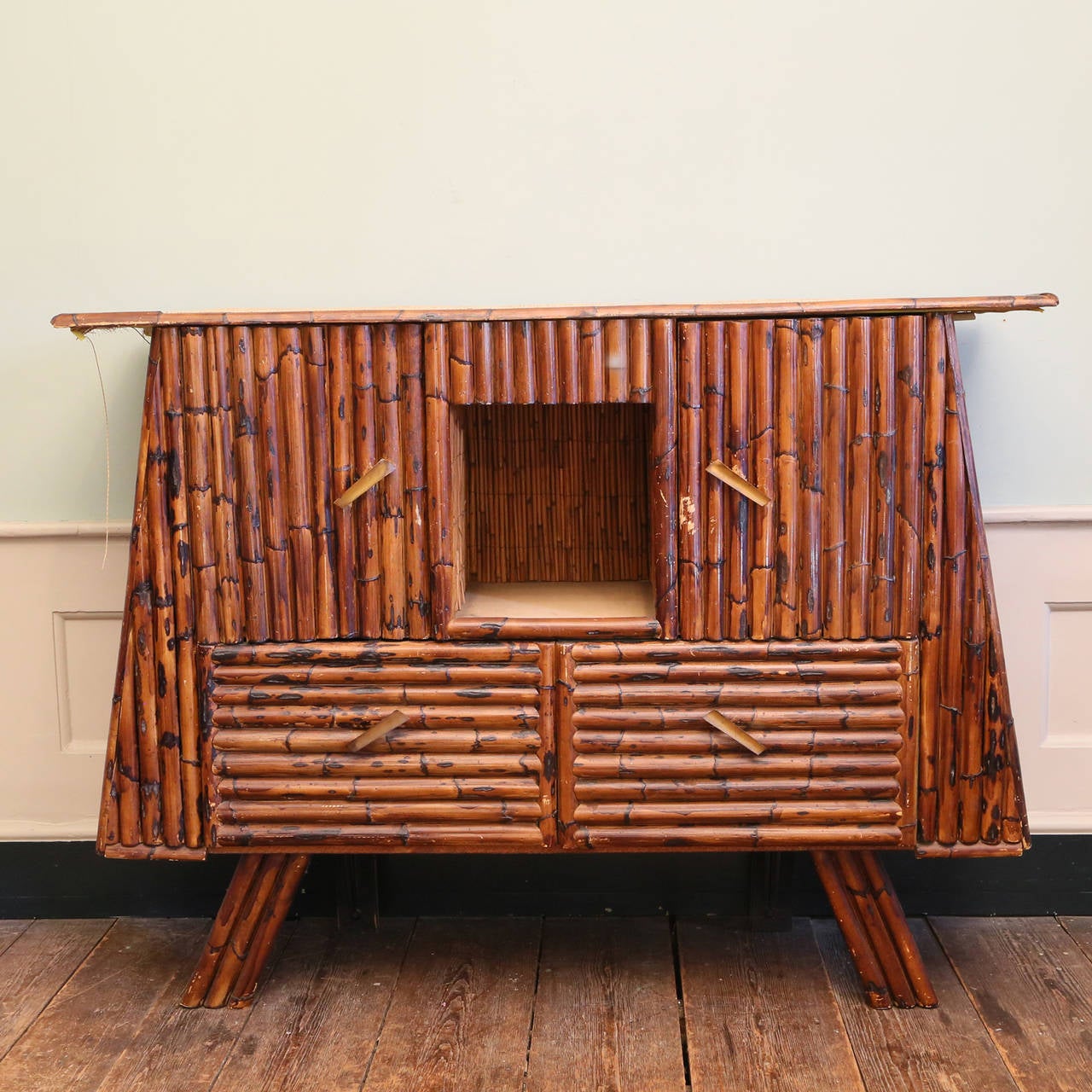 A Tiki bamboo drinks cabinet, the trapezoid body containing cupboards and fall-front storage.

Available to view at Brunswick House, London

Width 157cm, height 117cm, depth 48.5 cm