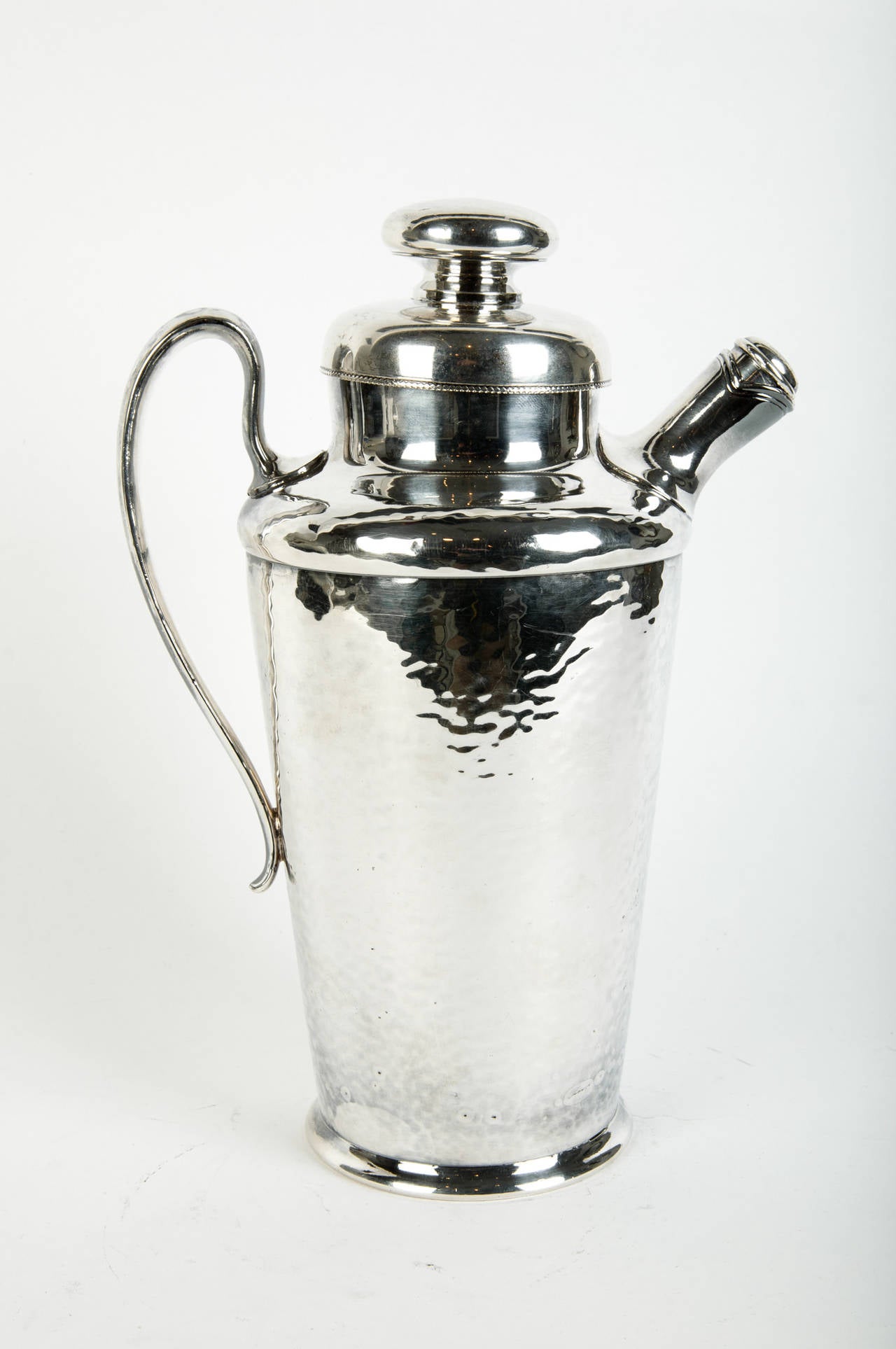 A 1950s vintage hammered cocktail shaker with handle and detachable sprout with screw cover. Handled lid with attached juicer.