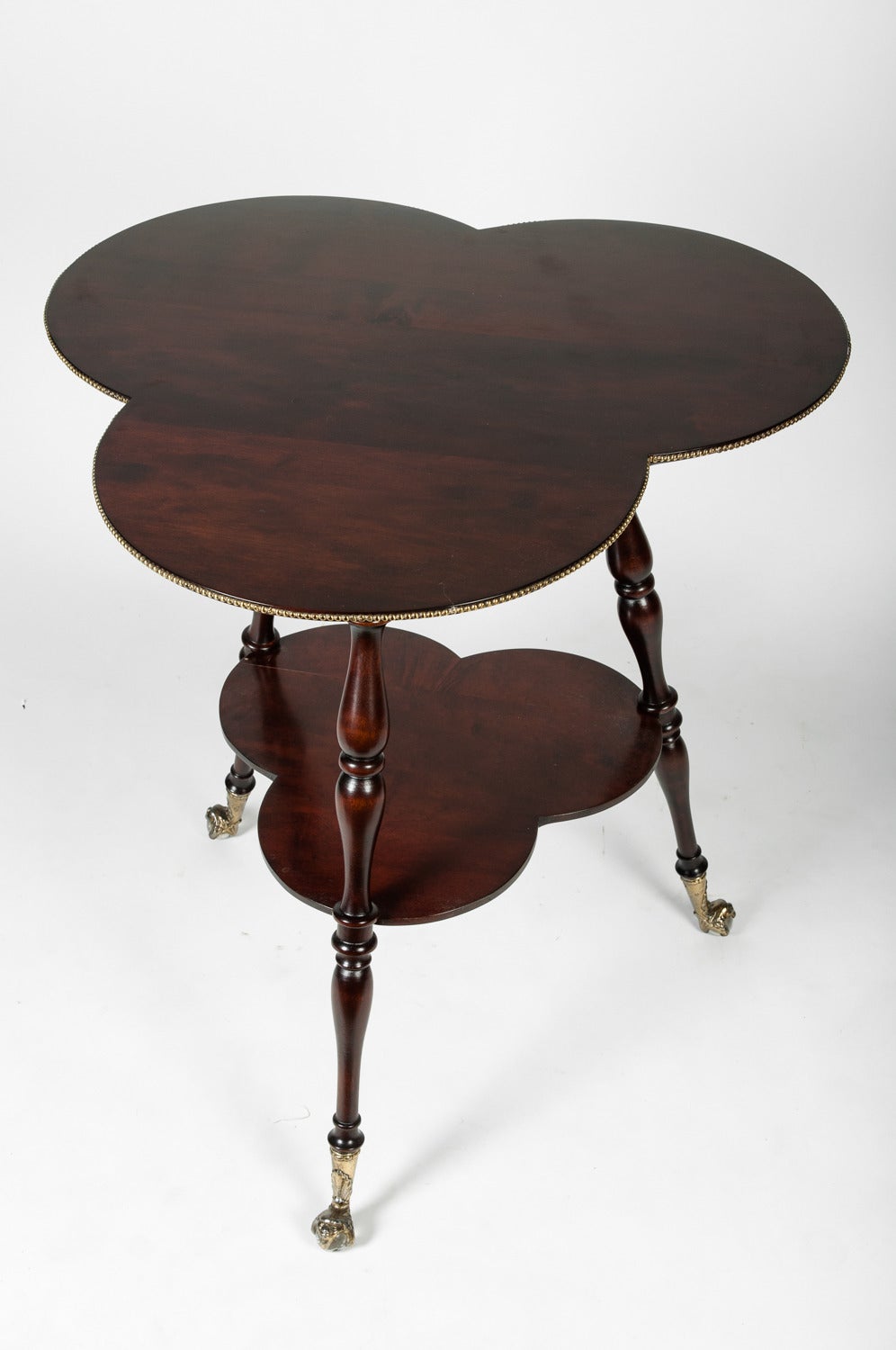 An antique English trefoil clover leaf side table wit bottom shelf and turned legs.