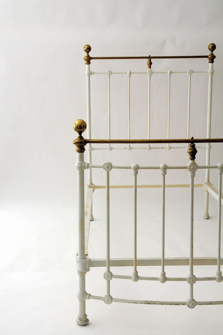Twin sized iron bed with brass accents.  Painted white.  Curved foot board.
