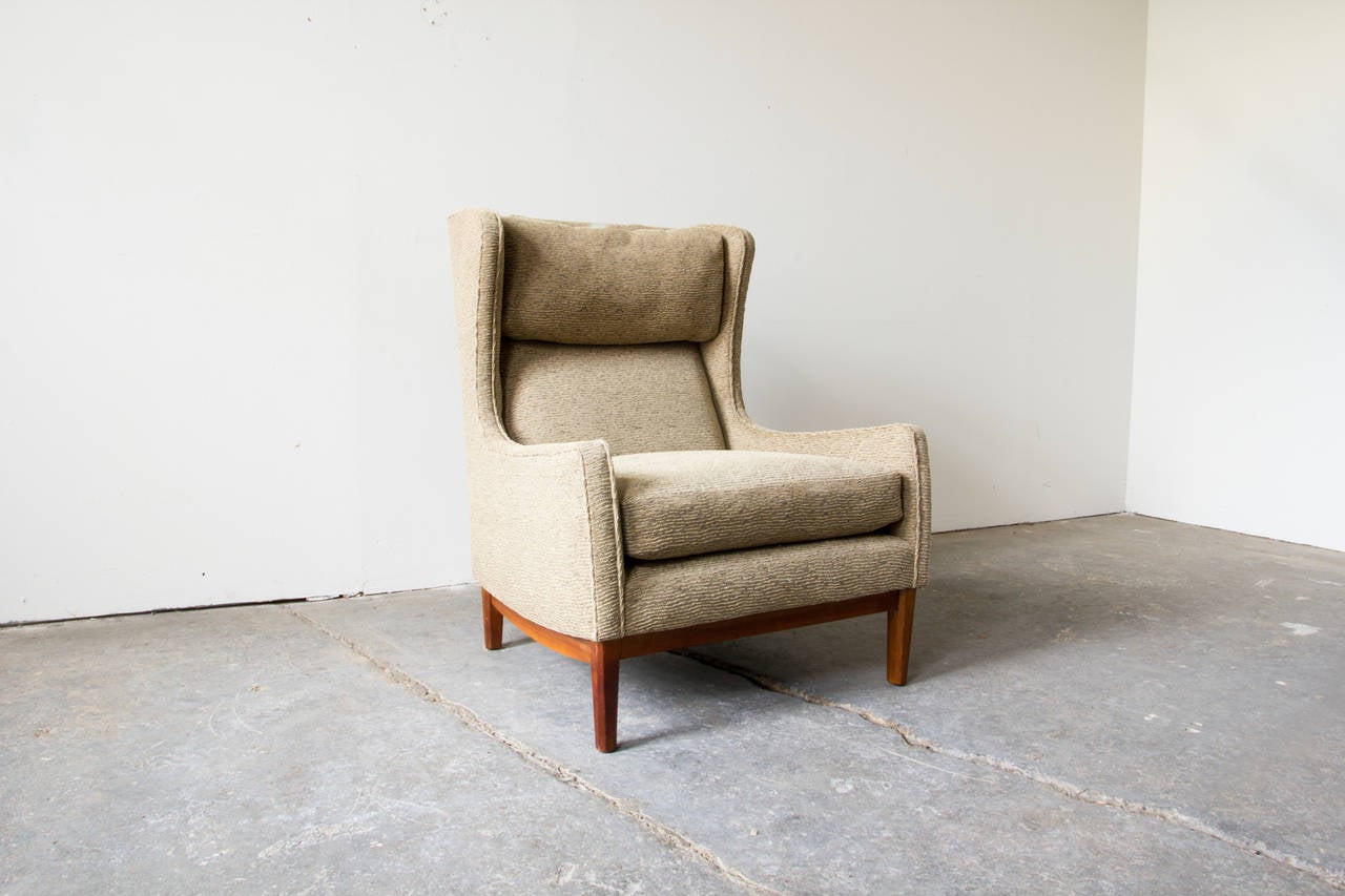 An elegant and organically formed wingback chair by W & J Sloane. This robust lounge features trim proportions, supplemented by chunky cushions and an adjustable head pillow. The legs and rails are solid walnut.