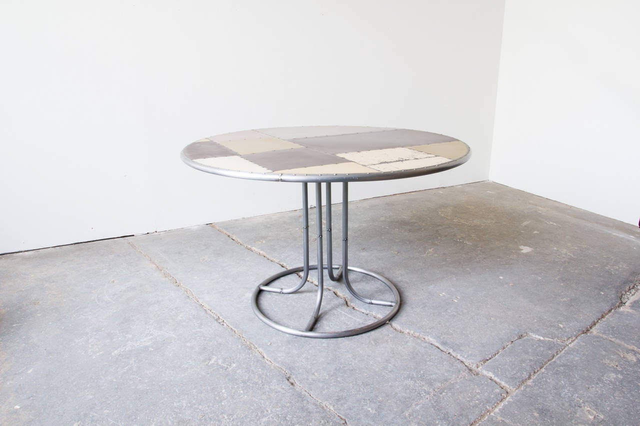 This dining table is wholly comprised of scrap metals salvaged from vintage appliances. It sits atop a tubular metal tulip base. Handmade in the United States.