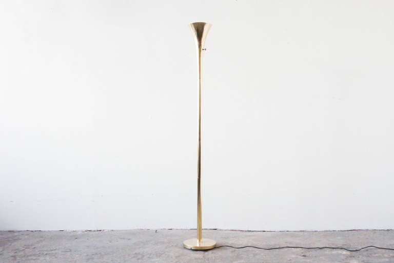This brass floor lamp by Laurel has a slender shape, and directs light only upward. The shade portion is made from solid cast brass.