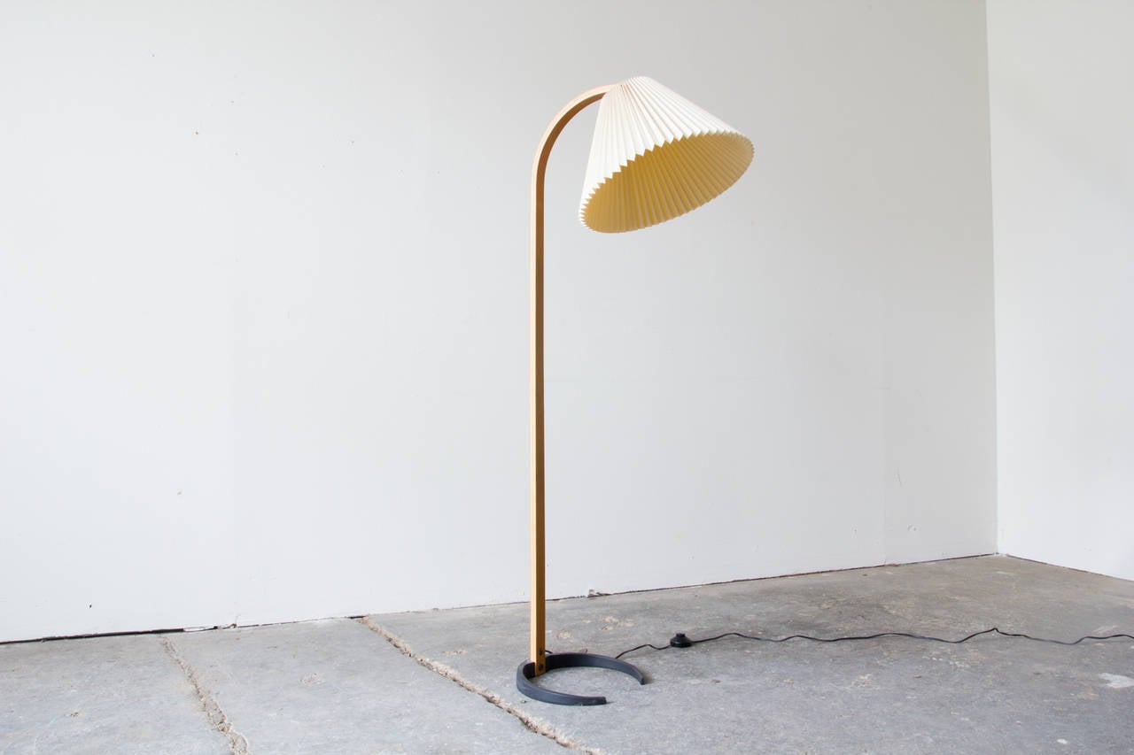 An exceptional Danish bentwood floor lamp by Caprani Light A/S. A slim yet robust crescent-form iron base is weighty enough to support this otherwise lightweight lamp. From it, a bentwood stem ascends vertically, bending at the top. The pleated