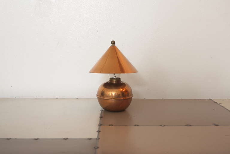 This small-sized copper table lamp was manufactured by Chase Brass & Copper Company. The base is rounded, and about the size of an apple. The cone shaped shade clips to the bulb.