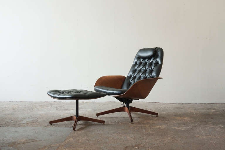 This lounge chair, by George Mulhauser for Plycraft, sits slightly higher than its earlier production. The chair complete with its original original ottoman, and both sit on frames of metal, surrounded by wood. The frames of each are of bent