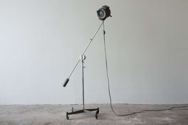 This early studio light stands on a four point base on casters. The boom pole is counterweighted, and the head can be tilted and swiveled to a number of positions.