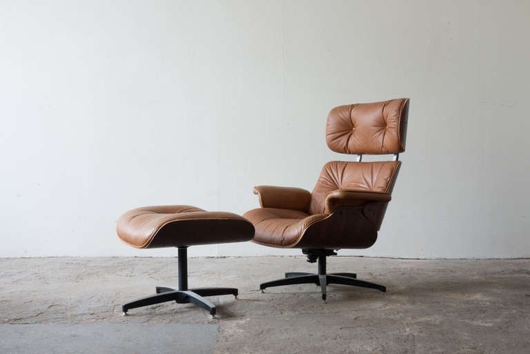 This lounge chair by Selig is inspired by the Eames' 670 lounge. It features a walnut finish, and maintains its original upholstery. The chair swivels and has a tilt adjustment beneath.