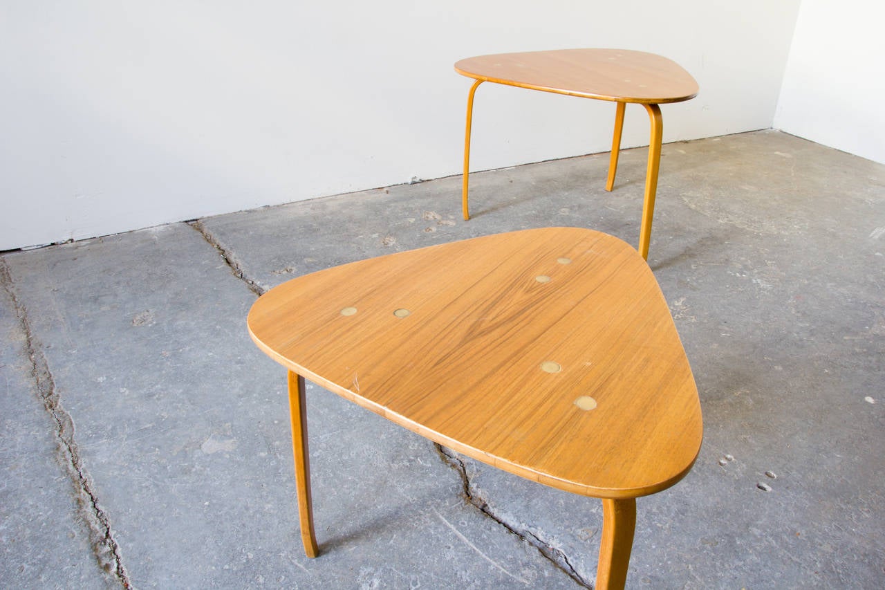 A pair of guitar pick tables by Yngve Ekström for DUX. The rounded triangle tops are accentuated by three multi-bent legs at each corner. The tops and the legs come together via brass hardware, which is inlaid on the surface. 

Large: H 19