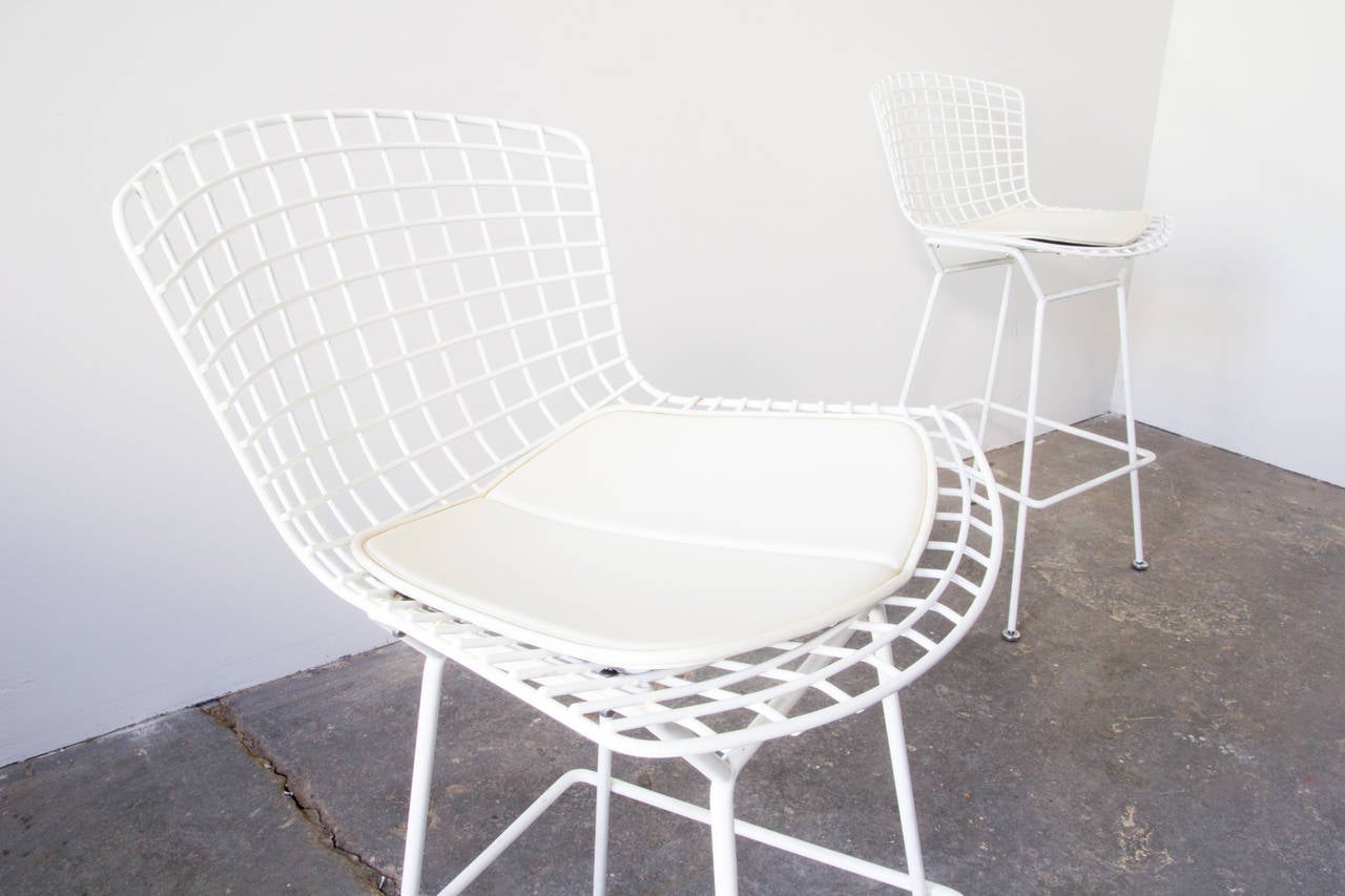 A pair of counter-height bar stools by Harry Bertoia for Knoll. The seats are wire mesh, affixed to welded steel-rod bases in a white powder coat finish. Good for outdoor or indoor use. Knoll vinyl seat pads are included.