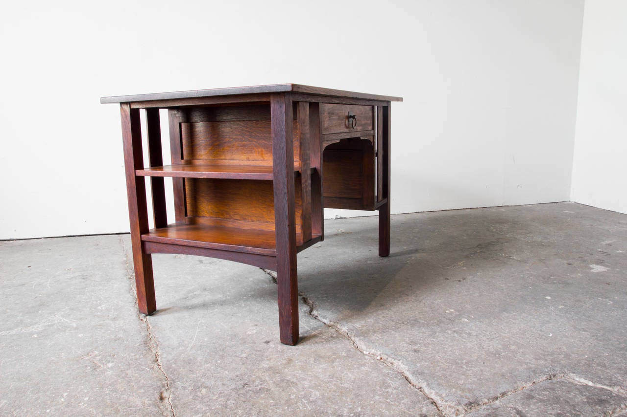 A handsome Craftsman desk in figural oak by Albert and John George Stickley of Stickley Brothers Co., Grand Rapids. Features of this piece include a burnished brass bullring pull, which opens sole drawer. Airy bookshelves on either side provide