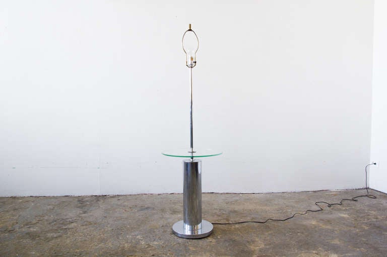 This Laurel lamp, of chromed steel, features an elegantly suspended circular table of glass. It is lightweight, and versatile in that it can fit into a number of design contexts.
